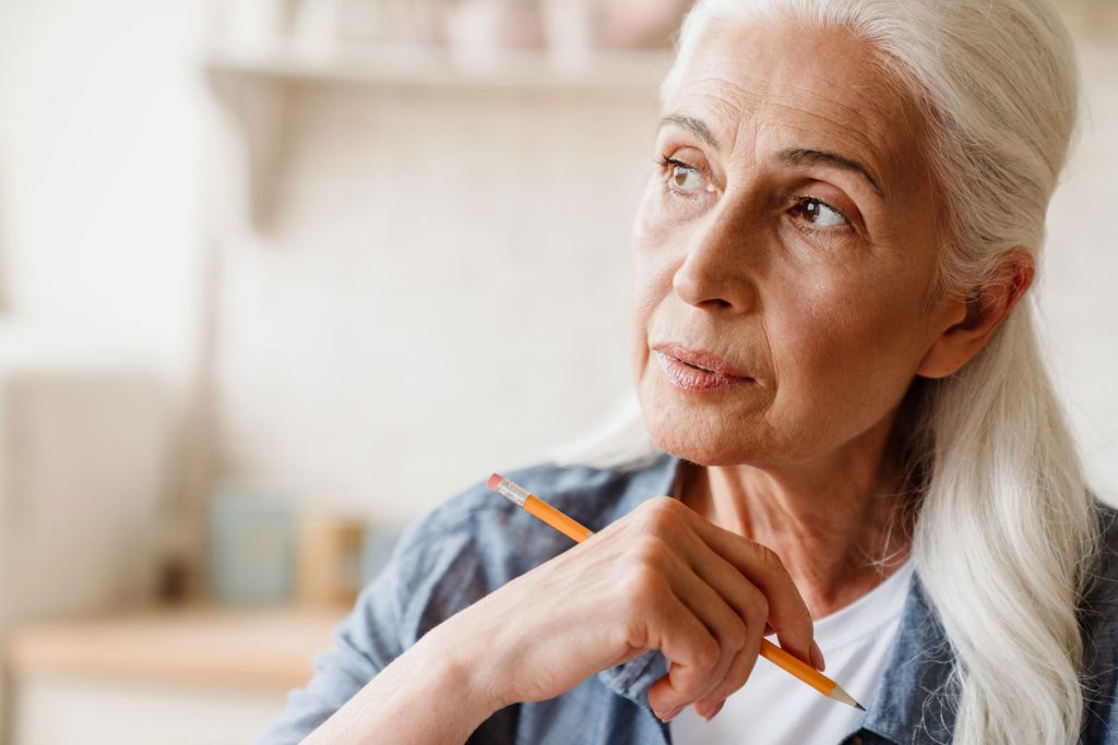 Adult woman holding a pencil, thinking.