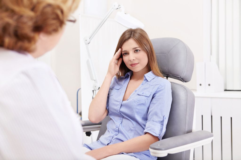 Woman in doctor's office with headache.