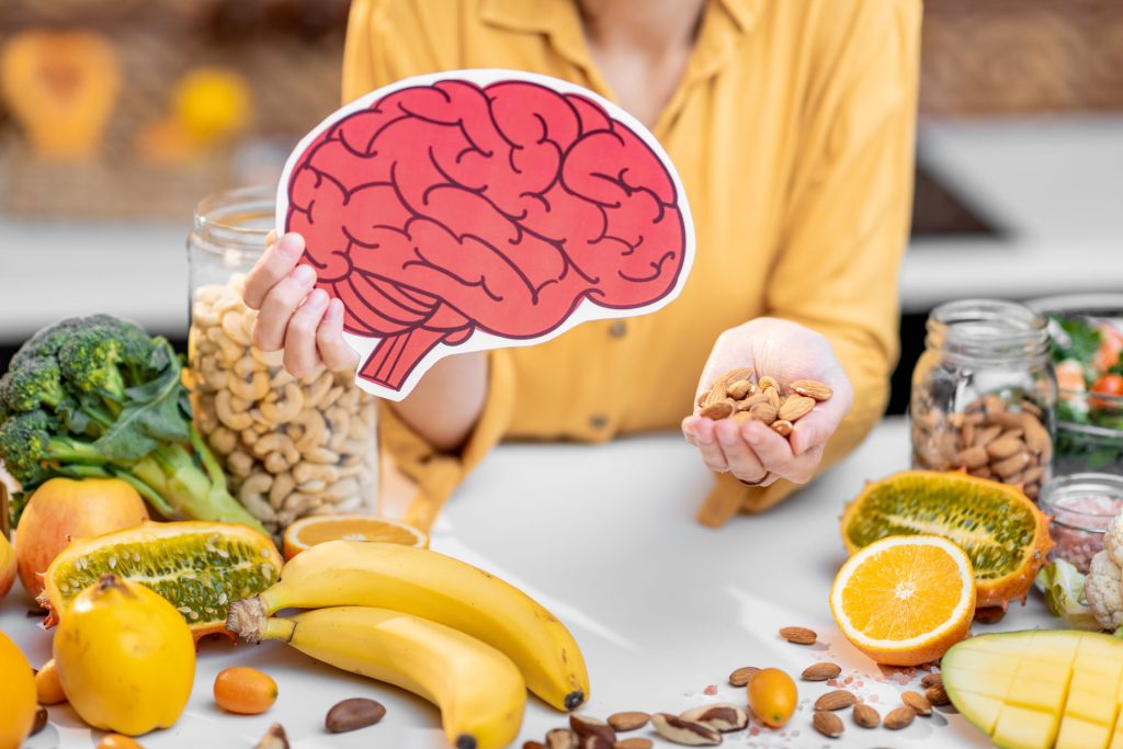 Healthy foods on the table with photo of an animated brain a woman is holding.