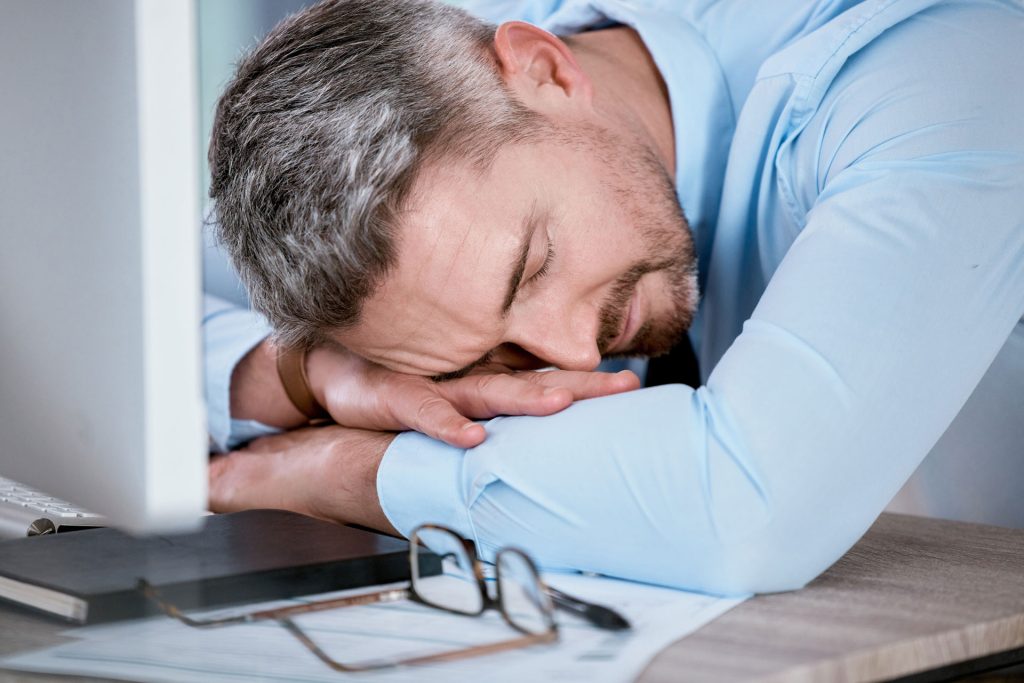 Tired middle-aged man sleeping in his desk.