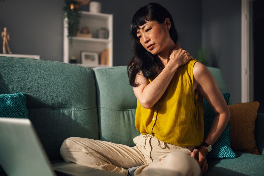 Woman sitting on a couch with neck pain.