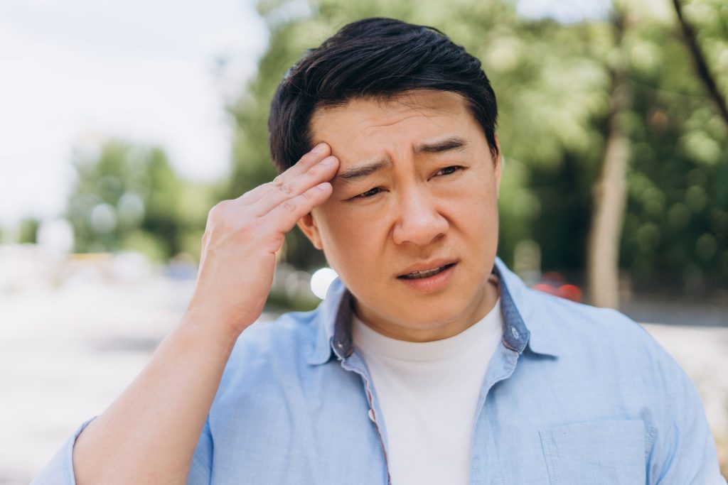 Asian man suffering from headache.